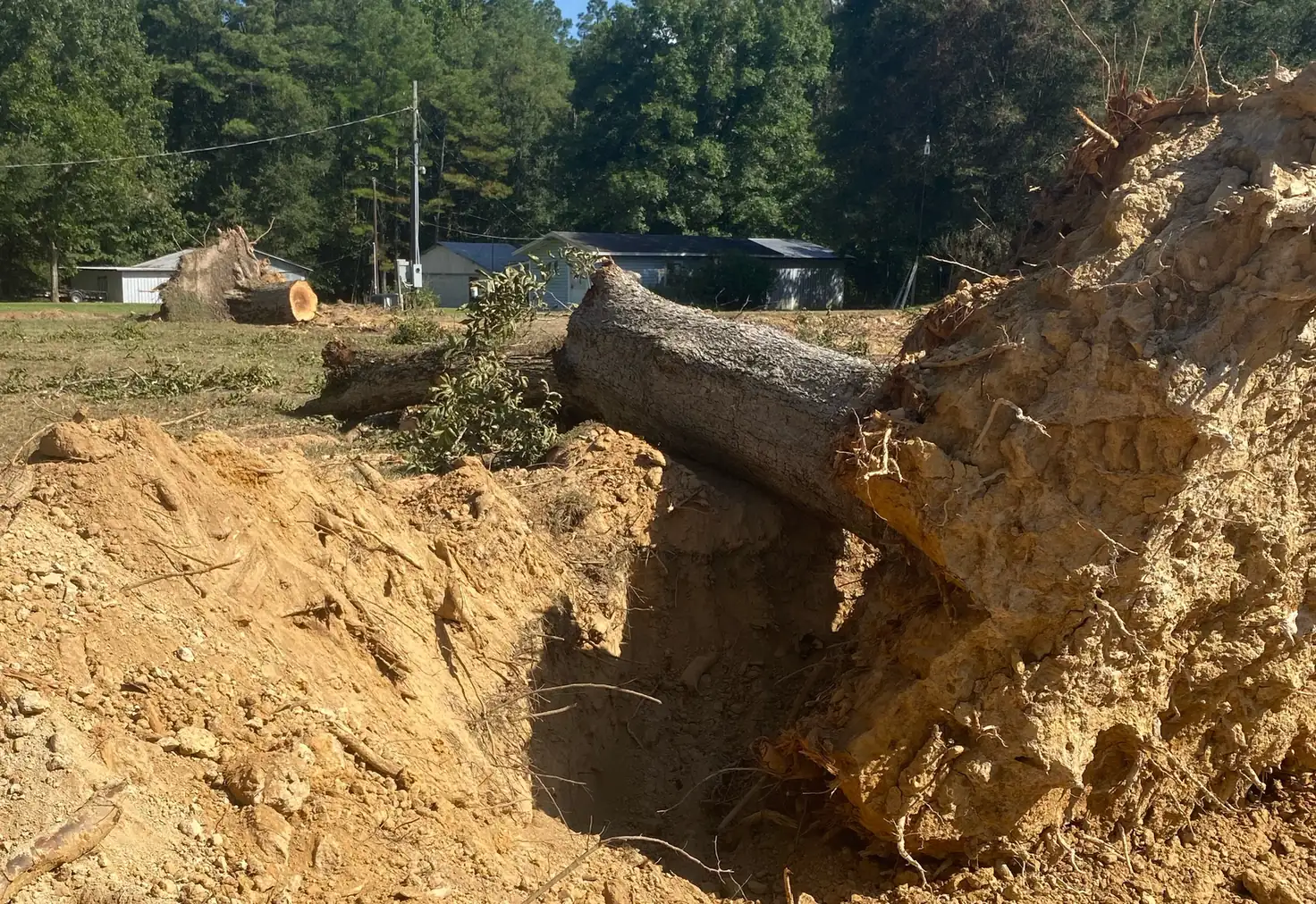 Large stump and trunk pulled out of the ground beside the open hole and spoil pile on a north Louisiana job