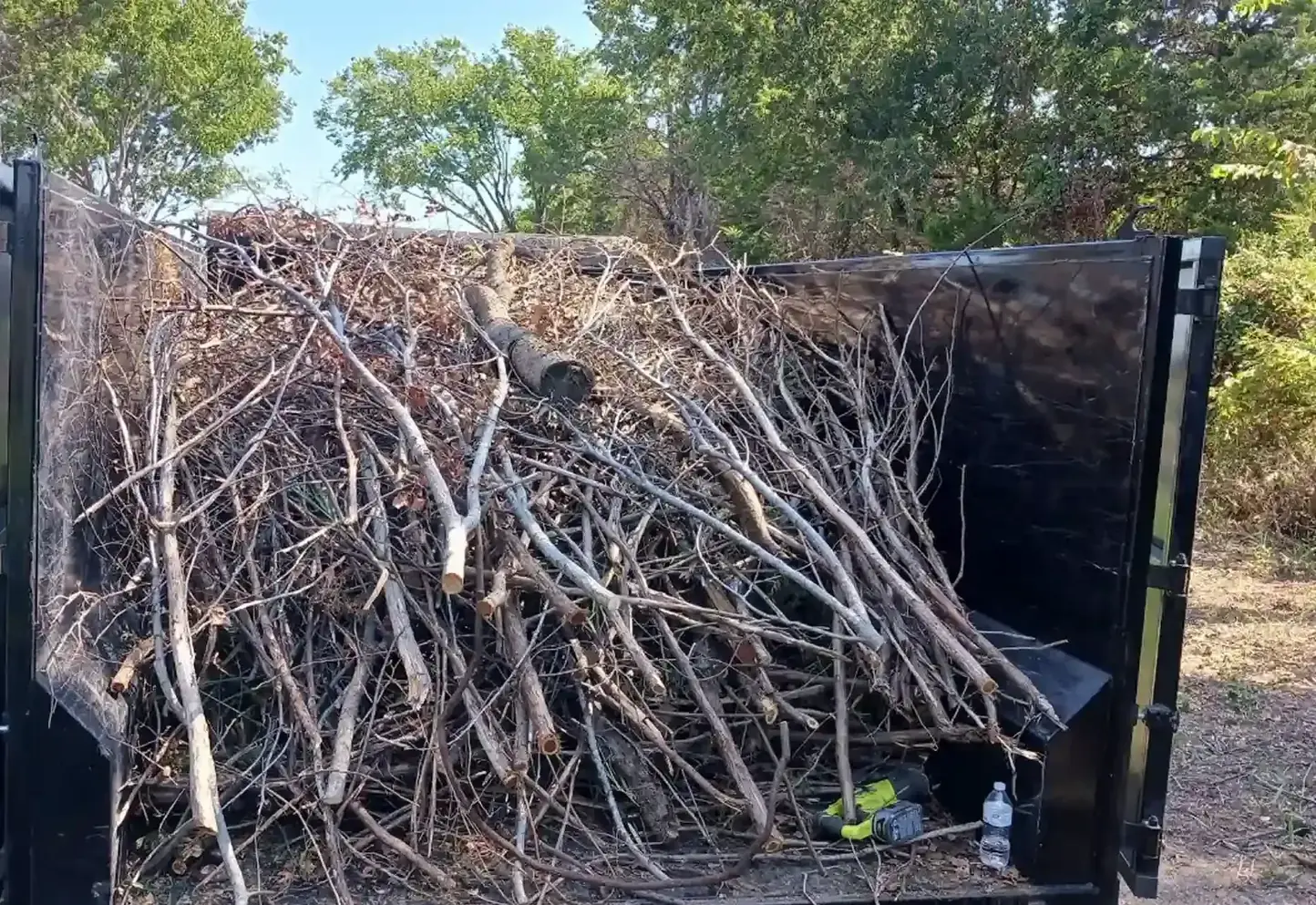 Dump trailer loaded to the top with storm-downed limbs and brush